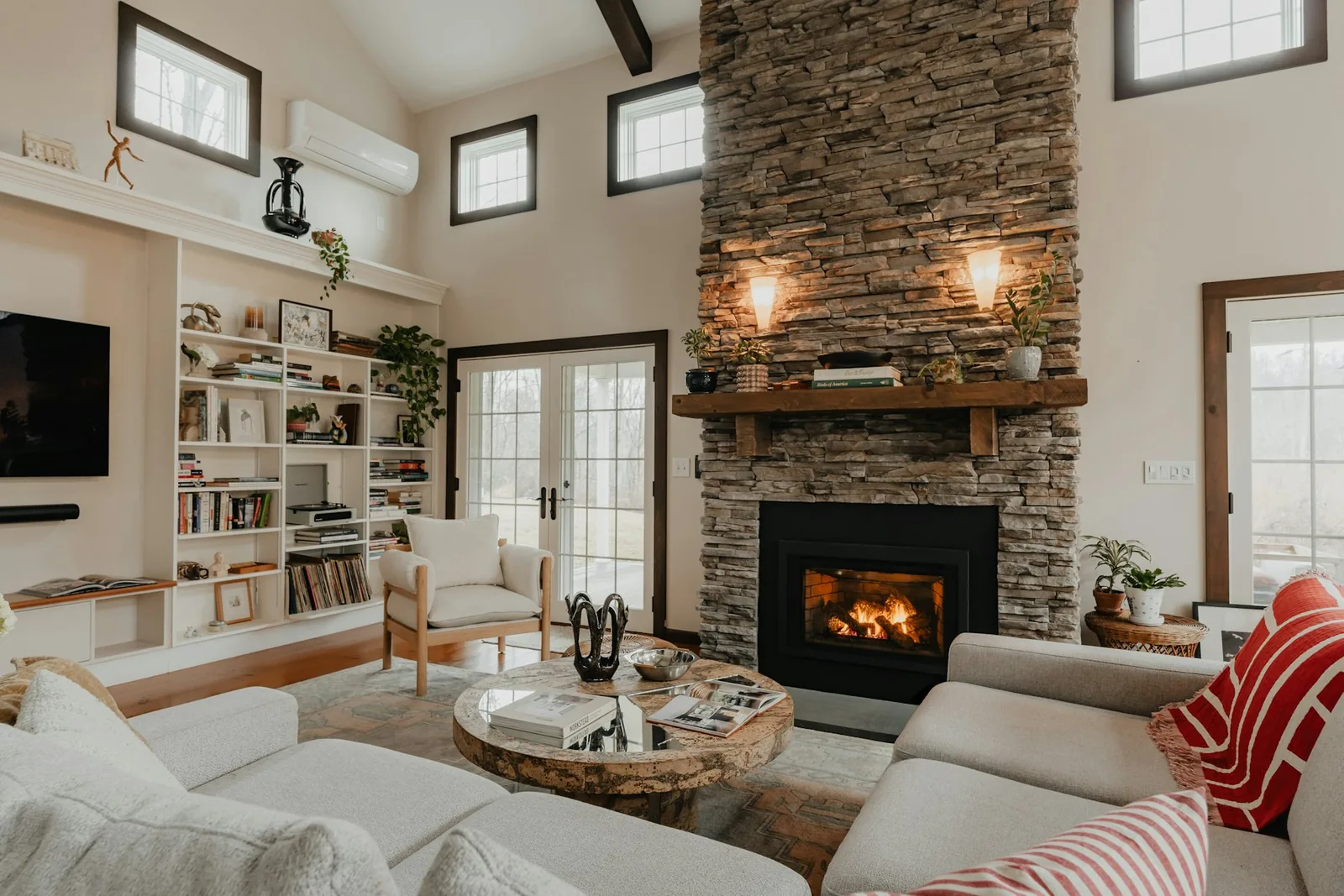 Glass-front fireplace insert in a stacked-stone surround with timber mantel